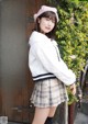 a japanese woman in a white sweater and plaid skirt posing for a magazine