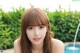 A woman with long brown hair and bangs posing by a pool.