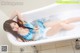 A woman in a blue bikini laying in a bathtub.