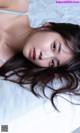 A woman laying on top of a bed with long brown hair.