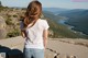 A woman standing on top of a mountain looking out over a valley.