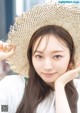 A woman with long brown hair wearing a straw hat.