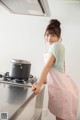 A woman standing in front of a stove with a pot on it.