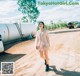 A woman walking down a dirt road next to a large tank.