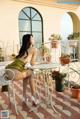 A woman sitting at a table on a balcony.