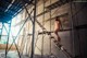 A naked woman standing on a ladder in an abandoned building.