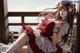 A woman in a red and white dress sitting on a wooden deck.