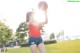 A woman in a red shirt and denim shorts holding a basketball.