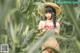 A woman in a straw hat standing in a field of corn.