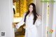 A woman in a white robe standing in front of a door.