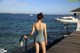 A woman in a bathing suit standing on a dock by the water.