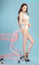 A woman in a white lingerie standing next to a pink shopping cart.