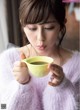 A woman holding a cup of green tea in her hands.