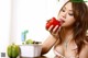 A woman is eating a red pepper while sitting at a table.