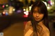 A woman standing in the middle of a street at night.