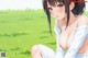 Anime girl sitting on the grass in a field.